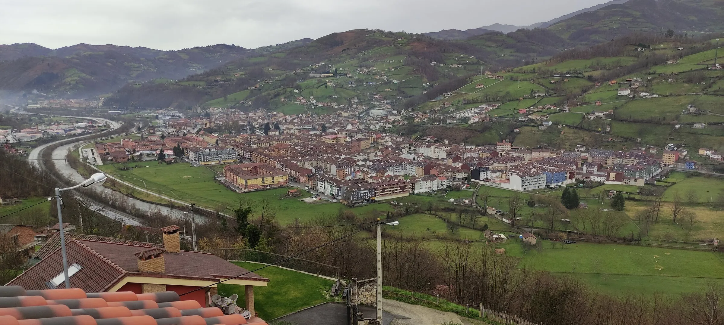 Valle visto desde un emplazamiento de Avanss, con un pueblo y prados entre montes.